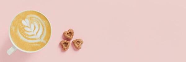 Web banner with delicious cappuccino and three pieces of sugar in the shape of hearts on pink background. photo