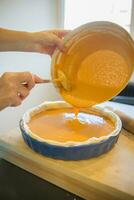 Close up of woman hands filling pumkin pie crust photo