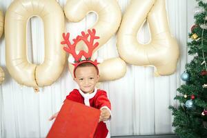 Merry Christmas 2024 concept Boy receives a gift from his mother at christmas photo