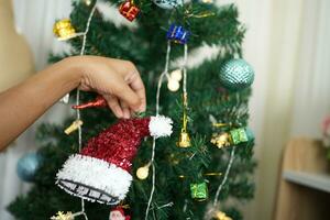 alegre Navidad 2024 concepto asiático mujer Decorar el Navidad árbol con vistoso Navidad pelotas. foto