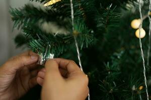 Merry Christmas 2024 concept Asian women decorate the Christmas tree with colorful Christmas balls. photo