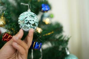 Merry Christmas 2024 concept Asian women decorate the Christmas tree with colorful Christmas balls. photo