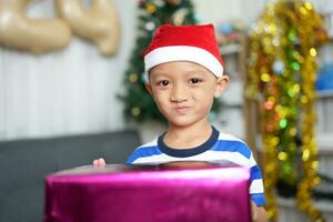 Merry Christmas 2024 concept A boy holding a gift box is happy to receive a present on Christmas Day. photo