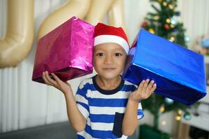 Merry Christmas 2024 concept A boy holding a gift box is happy to receive a present on Christmas Day. photo