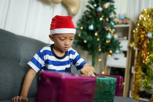 Merry Christmas 2024 concept A boy holding a gift box is happy to receive a present on Christmas Day. photo