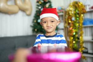 Merry Christmas 2024 concept A boy holding a gift box is happy to receive a present on Christmas Day. photo