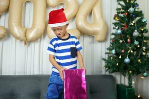 Merry Christmas 2024 concept A boy holding a gift box is happy to receive a present on Christmas Day. photo