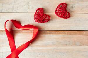 Red silk ribbon in shape of a heart on a wooden background. Valentine's day concept. Place for text. photo