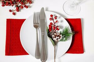 Christmas table setting. Plate and cutlery on red napkin. Decoration for festive dinner. photo