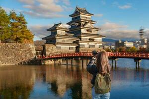 mujer turista visitando en matsumoto, contento viajero tomando foto matsumoto castillo o cuervo castillo. punto de referencia y popular para turistas atracción en matsumoto, nagano, Japón. viaje y vacaciones concepto
