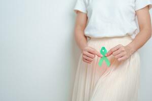 mujer participación verde azulado cinta en abdomen para enero cervical cáncer conciencia mes. útero y ovarios, cuello uterino, endometriosis, histerectomía, uterino fibromas, reproductivo y mundo cáncer día concepto foto