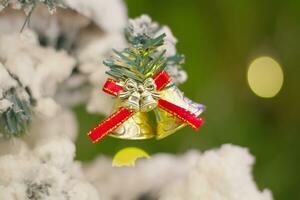 plata campanas colgar en un Navidad árbol cubierto en blanco nieve foto