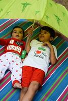 dos contento Niños en sociedad parque, contento asiático hermanos quien son sonriente felizmente juntos. hermanos jugar al aire libre en verano, mejor amigos. niñito bebé chico jugando con su contento hermano en el jardín foto