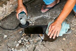 A technician is sharpening a knife for use in construction work. photo