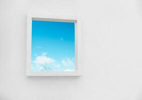 White Wall texture of concrete with open window against blue sky and clouds inSummer, Exterior Cement building with border frame with Spring sky,Ant view Modern architecture. Minimal design photo