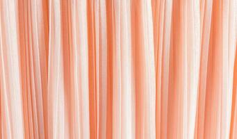 delicate chic textile background of peach color. pleats of chiffon or silk fabric. Abstract background for design. Color of the Year 2024 Peach Fuzz. photo