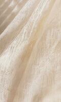 vertical ver de elegante suave pliegues de fábrica tela con ornamento. beige, champán color, Marfil, cremoso. Boda tela resumen antecedentes. foto