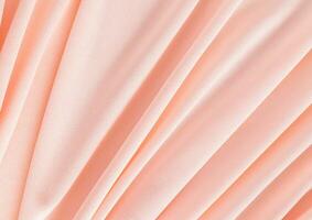 Elegant textile background in peach color with soft pleats. Festive background of the color of the year 2024 peach fuzz. A copy space. photo