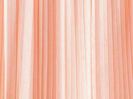 Abstract background of soft pleats of peach color quilled fabric. Festive background for design. A copy space. Color of the Year 2024 Peach Fuzz photo