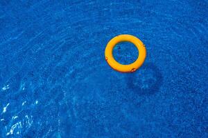 Top view of lifebuoy floating in blue swimming pool, soft focus. photo