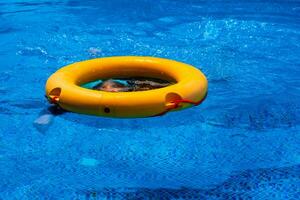 Top view of lifebuoy floating in blue swimming pool, soft focus. photo