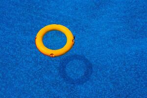 Top view of lifebuoy floating in blue swimming pool, soft focus. photo