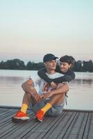 Cute young couple on the shore of a lake looking into their future during sunset. 20-year-old couple hugging photo