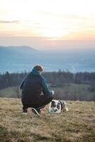 Young cynologist, a dog trainer trains a four-legged pet Australian Shepherd in basic commands using treats. Love between dog and human photo