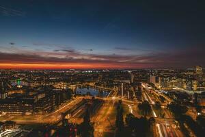 Aerial view of nightlife in the modern city of Rotterdam in the Netherlands. Red glow from the setting sun in the background photo