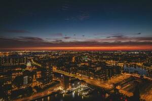 Aerial view of nightlife in the modern city of Rotterdam in the Netherlands. Red glow from the setting sun in the background photo