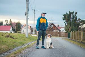 Young cynologist, a dog trainer trains a four-legged pet Australian Shepherd in basic commands using treats. Love between dog and human. Cuteness photo