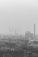 Smog hovering over the city of Amsterdam in black and white format. In the distance, the change in energy availability within wind farms photo