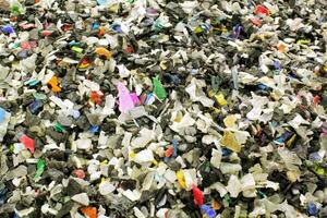 Shredded plastic pieces prepare for recycling. Raw cables material for reproduction. Sorting garbage on waste plant. Pile of scrap bottles on trash storage factory. Environmental concept photo