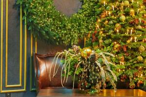 Christmas tree with garland lights and room decor with leather chair, New Year holiday. Interior living room fir tree with balls and candles photo