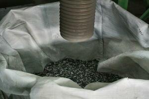 Shredded plastic pieces prepare for recycling. Raw cables material for reproduction. Sorting garbage on waste plant. Pile of scrap bottles on trash storage factory. Environmental concept photo