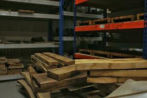 Close-up of wooden planks at lumber warehouse. Storage shelves with panel in lumberyard. Background of boards on shop. Processed timber blocks products in market. Raw wood drying in carpenter workshop photo