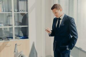 Serious businessman with phone, blinds casting shadows photo