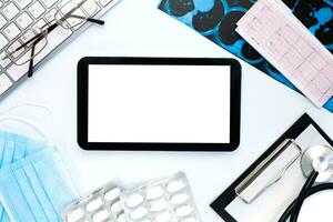 Top view of doctor's workplace with digital tablet, medical stethoscope, pills, CT scan and cardiogram on white background. Flatlay composition. Medical concept. photo