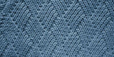 The texture of a knitted woolen fabric into a rhombus blue gray color. Abstract background. Wallpaper. Banner. Close-up. Selective focus. photo