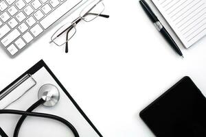 Medical stethoscope, keyboard, notebook with pen and black tablet on white background. Doctor's workplace. Top view. Flatlay composition. Medical concept. photo