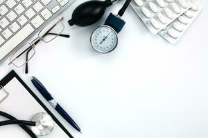 Flatlay composition with pulsimeter, pills, medical stethoscope and clipboard on white background. Top view of doctor desk. Medical concept. Copy space. photo