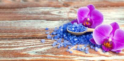 Sea salt and orchids on wooden background. Spa treatments. Close-up. Place for text. photo