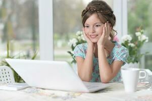 Cute and happy little girl children using laptop computer photo