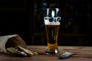 Glass of beer and dried fish on a wooden table photo