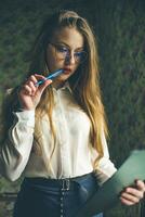 A girl in business clothes and glasses holds a black folder in her hands. photo