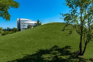 Manicured courtyard of luxury mansion with hill covered with green grass in summer photo