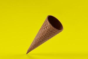 Empty, tasty wafer cone for ice cream against yellow background. Concept of food, treats. Mockup, template for your advertising and design. Close up photo
