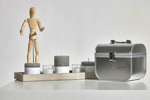 Table, different sized and colors candles with copy space on wooden stand, figurine of human, silver bag in form of chest. Isolated on white. Close up photo