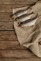 Three salted air-dried roach on sackcloth on wooden background photo