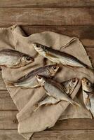 Pile of salted air-dried fish on sackcloth on wooden background photo